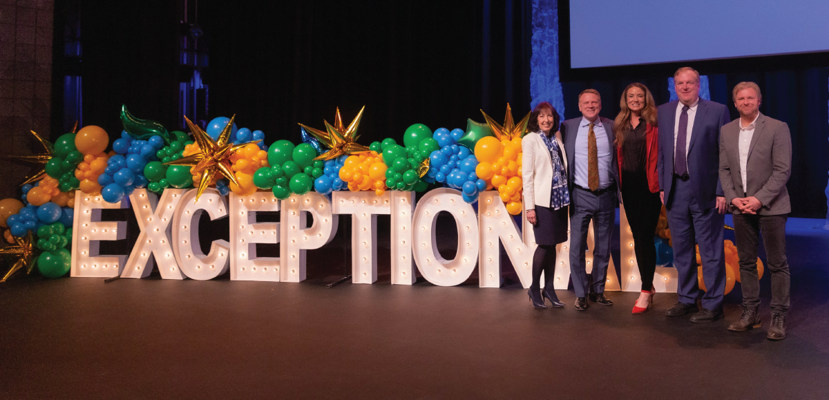 City leaders in front of large letters spelling exceptional