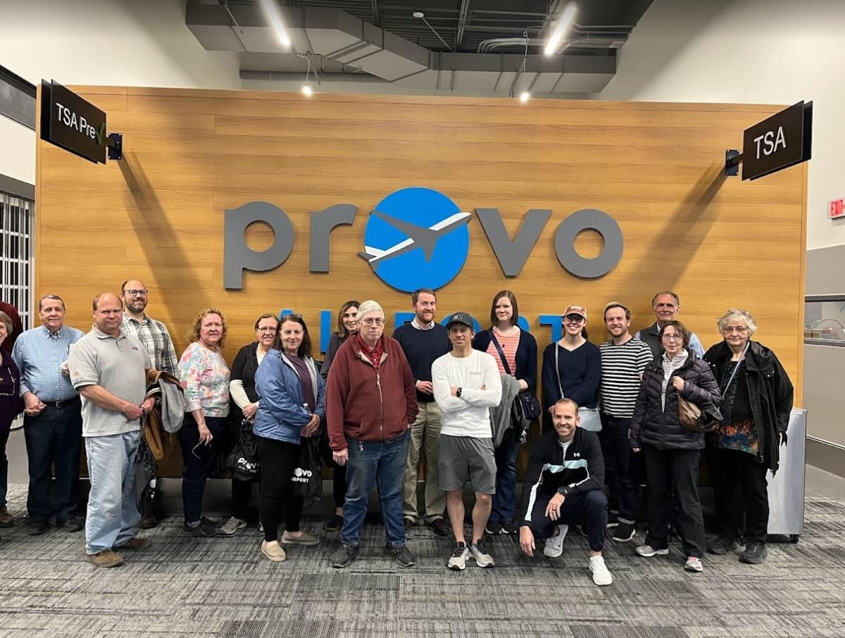 Group of citizens standing in front of the Provo Airport Sign